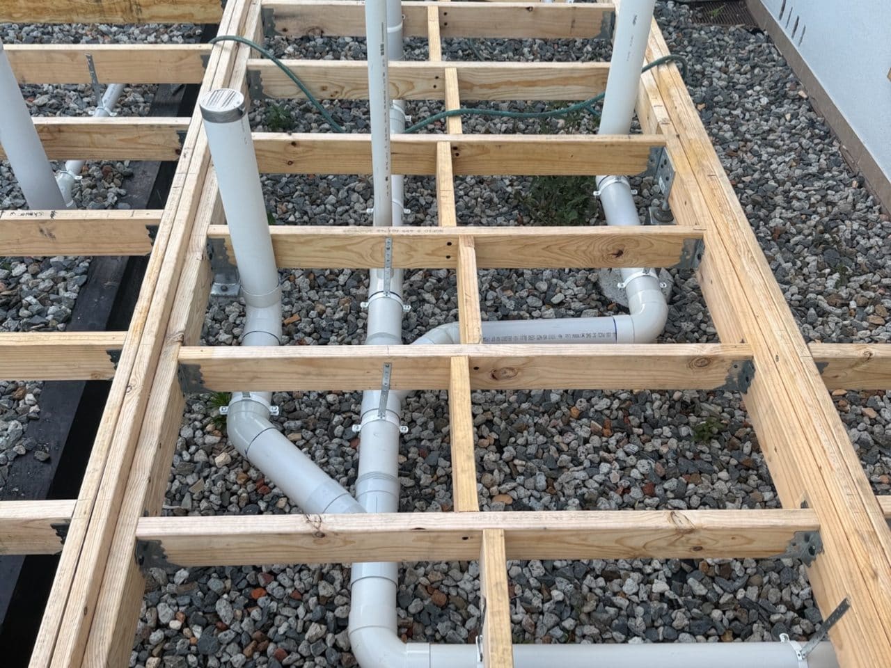 New pipework run beneath a timber floor frame before the floor goes down