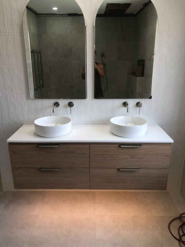 Double vanity with round vessel basins, wall mixers and arched mirrors