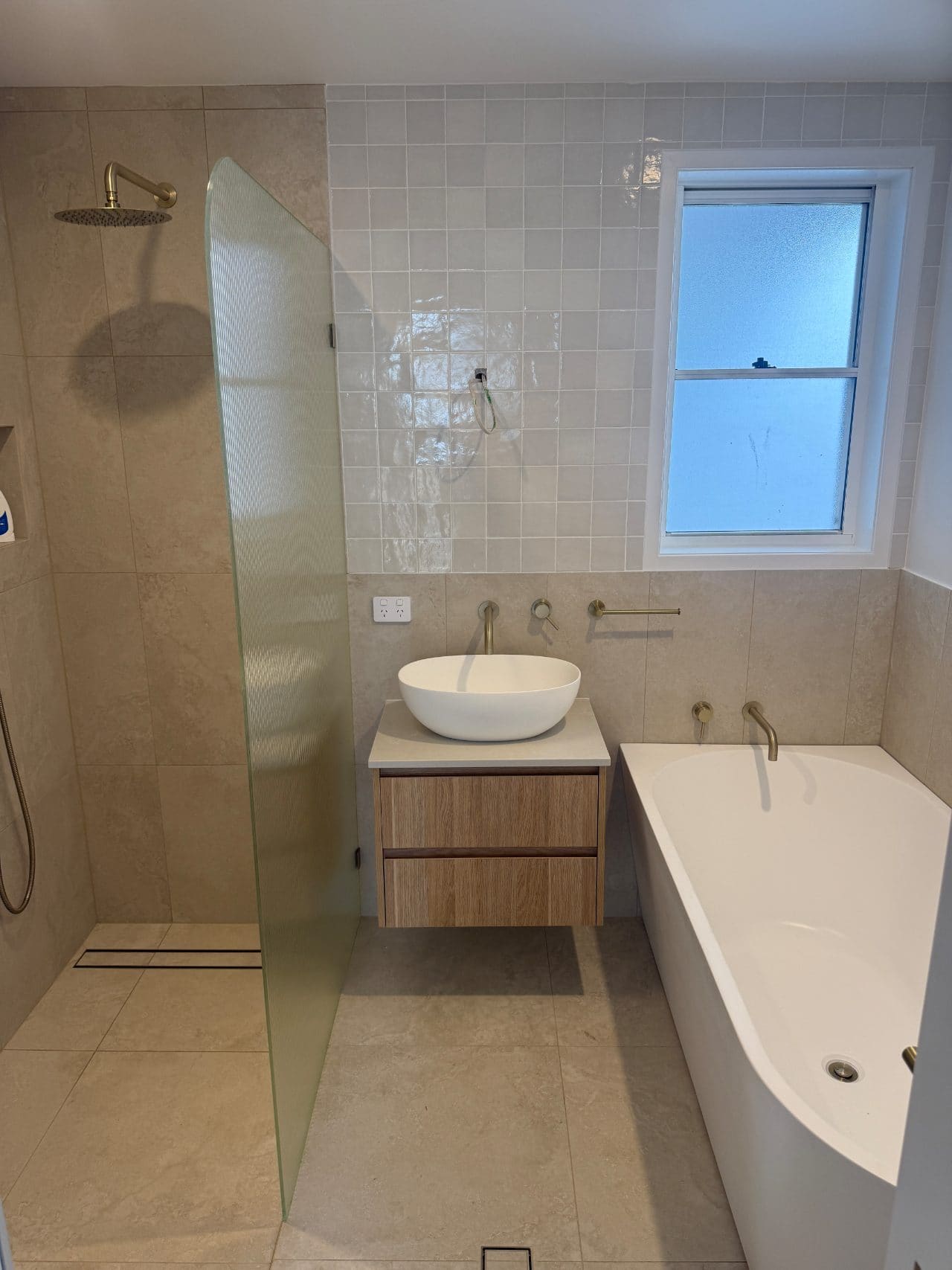 Walk-in shower, vessel basin and corner bath with brushed brass tapware