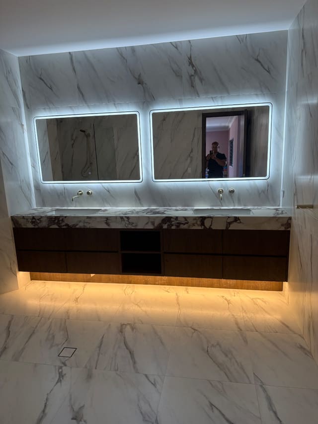 Double marble vanity with backlit mirrors in a completed bathroom renovation