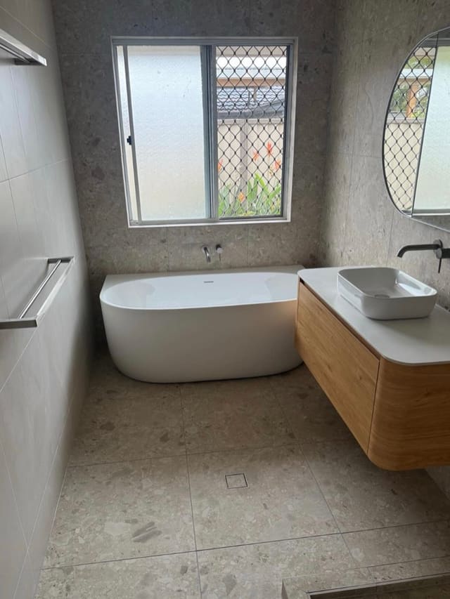 Curved oak vanity and freestanding bath in a completed bathroom