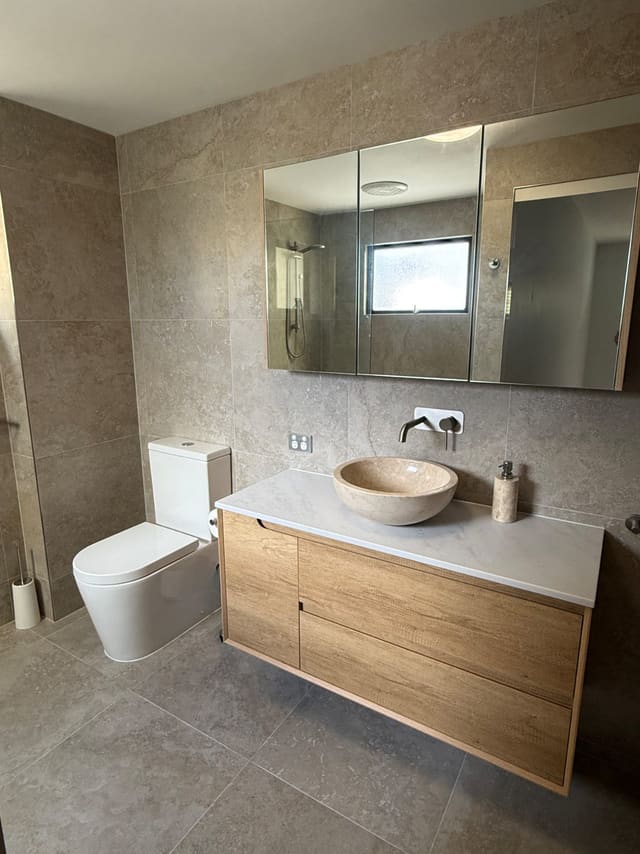 Stone vessel basin, mirrored shaving cabinet and wall-mounted mixer in a renovated bathroom