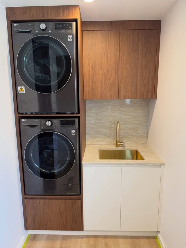 Laundry with stacked washer and dryer, brass sink and gooseneck mixer