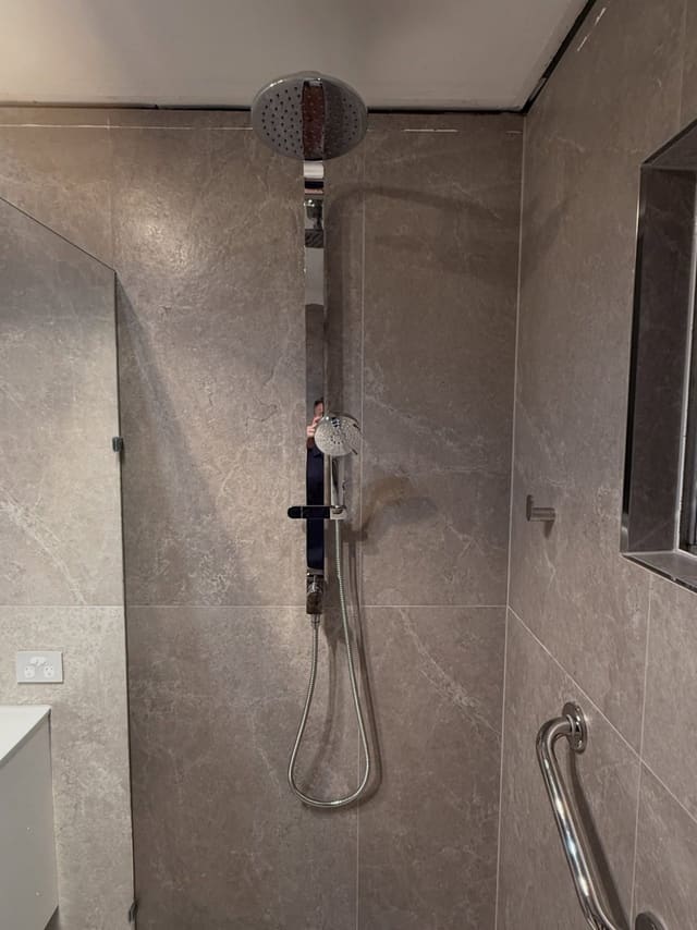 Walk-in shower with an overhead rose, hand shower on a rail and a grab rail
